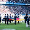 FootballR - NFL - An einem sonnigen Tag tragen uniformierte Bundeswehrangehörige vor einem vollen Stadionpublikum eine große deutsche Flagge über ein Feld, was an eine formelle Zeremonie oder ein Eröffnungsritual eines Spiels der European League of Football erinnert. Diese Beschreibung wurde automatisch generiert.