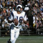 FootballR - NFL - Ein Quarterback in weiß-blauer Uniform mit der Nummer 18, identifiziert als NFL MVP Roman Gabriel, sucht während eines sonnigen Footballspiels nach einem freien Receiver. Er hält den Football in seiner rechten Diese Beschreibung wurde automatisch generiert.