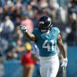 FootballR - NFL - Ein Footballspieler mit der Nummer 41, Josh Allen , feiert auf dem Feld mit geballter Faust, während die Menge im Hintergrund in einem sonnigen Stadion zusieht, möglicherweise nachdem er einen Mega-Vertrag mit den Jaguars unterzeichnet hat. Diese Beschreibung wurde automatisch generiert.