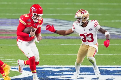 FootballR - NFL - Super Bowl Rückspiel - Ein Quarterback der Kansas City Chiefs Patrick Mahomes versucht, einem Tackle eines Verteidigers der San Francisco 49ers Logan Ryan während eines wichtigen American-Football-Spiels auszuweichen und unterstreicht damit die Intensität und Athletik des Sports, während Logan Ryans NFL Diese Beschreibung wurde automatisch generiert.