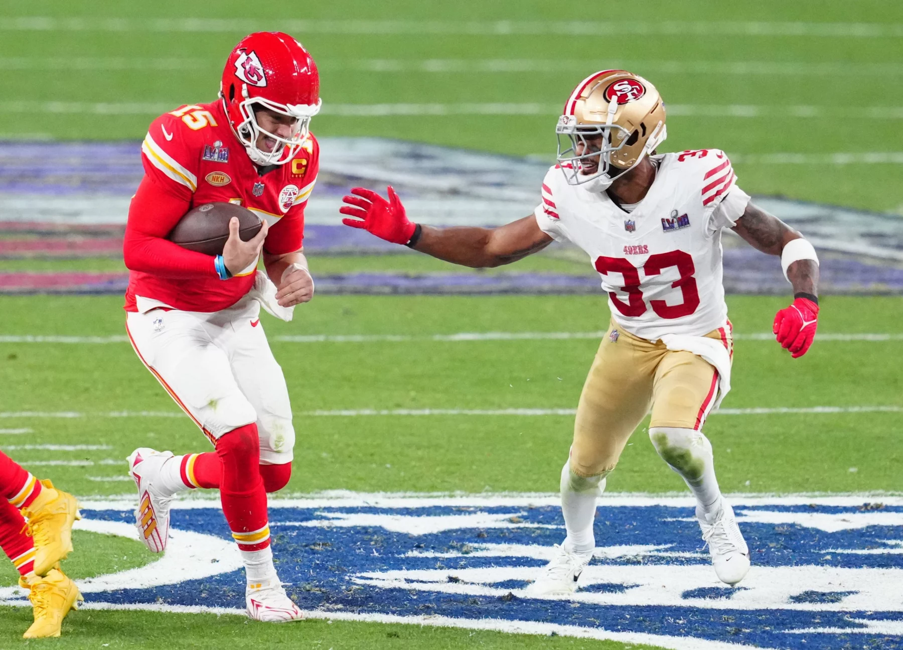 FootballR - NFL - Super Bowl Rückspiel - Ein Quarterback der Kansas City Chiefs Patrick Mahomes versucht, einem Tackle eines Verteidigers der San Francisco 49ers Logan Ryan während eines wichtigen American-Football-Spiels auszuweichen und unterstreicht damit die Intensität und Athletik des Sports, während Logan Ryans NFL Diese Beschreibung wurde automatisch generiert.