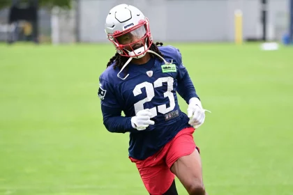 FootballR - NFL - Kyle Dugger, ein American-Football-Safety für die New England Patriots, trägt die Nummer 23, trainiert auf dem Feld, trägt einen weißen Helm, ein blaues Trikot und rote Shorts, konzentriert und Diese Beschreibung wurde automatisch generiert.