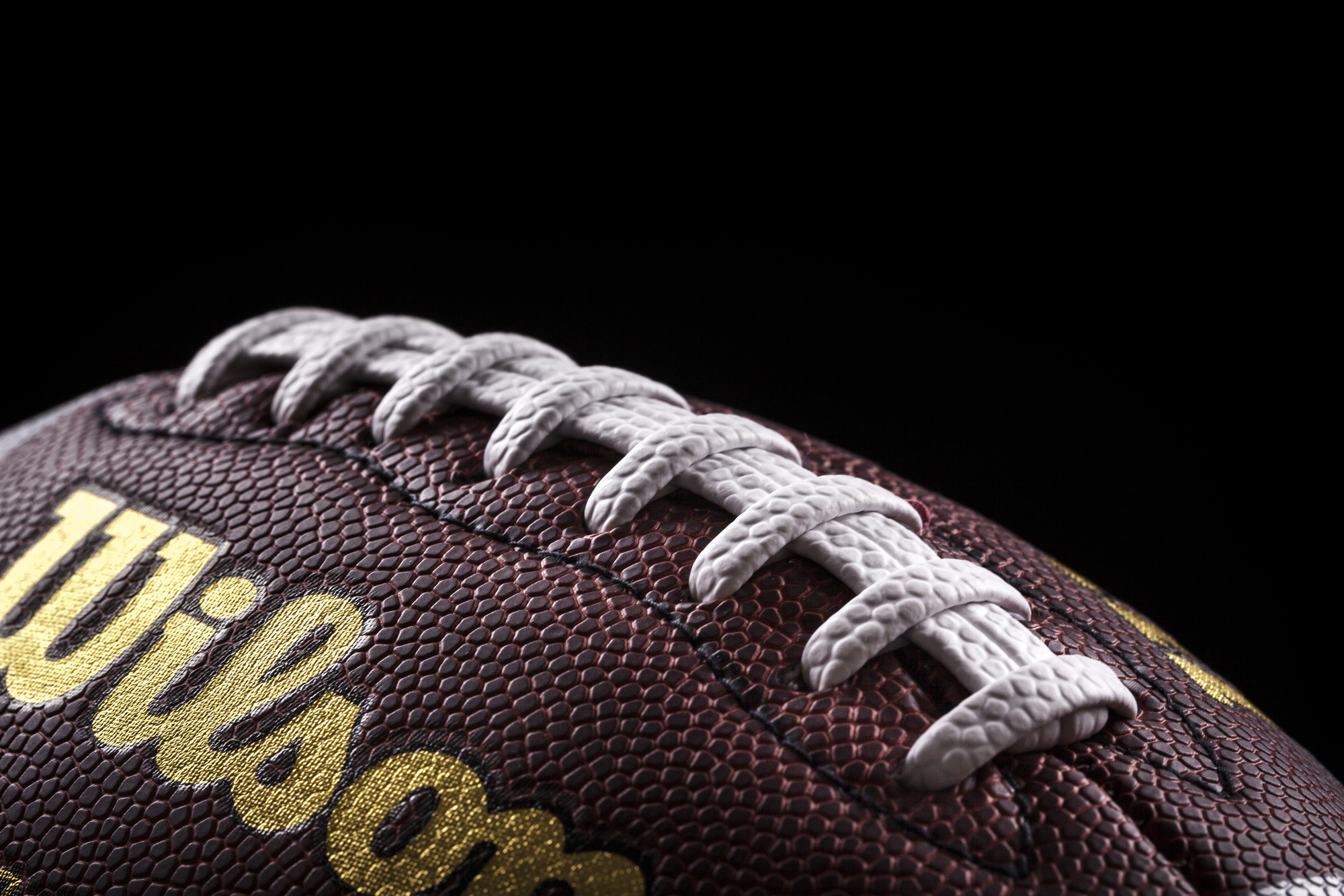 Championship Game - Prime Days - NFL - Nahaufnahme eines traditionellen American Footballs vor schwarzem Hintergrund. Die strukturierte Oberfläche aus braunem Leder ist sichtbar, mit weißen Schnürsenkeln in der Mitte. Die Worte „Wilson NFL Duke Replica“ sind in Gold auf den Ball gedruckt und geben die Marke und das Modell an. Der Fokus hebt die Nähte und die Maserung hervor. Diese Beschreibung wurde automatisch generiert. Nordic Storm