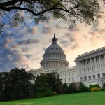 FootballR - NFL Draft 2027 - NFL Senat für Washington Commanders. Das Kapitol in Washington D.C. steht majestätisch unter einem Himmel mit vereinzelten Wolken in der Abenddämmerung. Die Kuppel ist markant, flankiert von klassischer Architektur und üppigem Grün, darunter ein großer Baum, dessen Äste von oben in den Rahmen hineinragen. Diese Beschreibung wurde automatisch generiert.