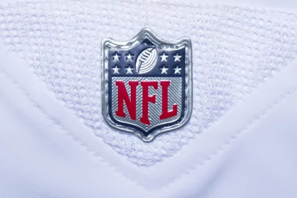 NFL Spielplan 2026 - 2025 Preseason -Rivalries Trikots - NFL-Fanartikel - NFL Spielplan 2025 - Nahaufnahme des NFL Spielplan 2024 -Logos auf einem weißen Footballtrikot. Das Logo zeigt ein Muster der amerikanischen Flagge mit Sternen und Streifen, ein Football-Symbol und fettgedruckte rote „NFL“-Buchstaben vor Diese Beschreibung wurde automatisch generiert.