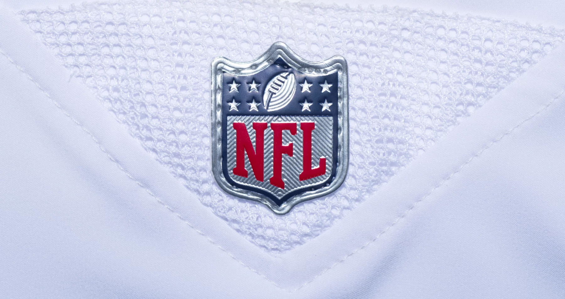 NFL Spielplan 2026 - 2025 Preseason -Rivalries Trikots - NFL-Fanartikel - NFL Spielplan 2025 - Nahaufnahme des NFL Spielplan 2024 -Logos auf einem weißen Footballtrikot. Das Logo zeigt ein Muster der amerikanischen Flagge mit Sternen und Streifen, ein Football-Symbol und fettgedruckte rote „NFL“-Buchstaben vor Diese Beschreibung wurde automatisch generiert.