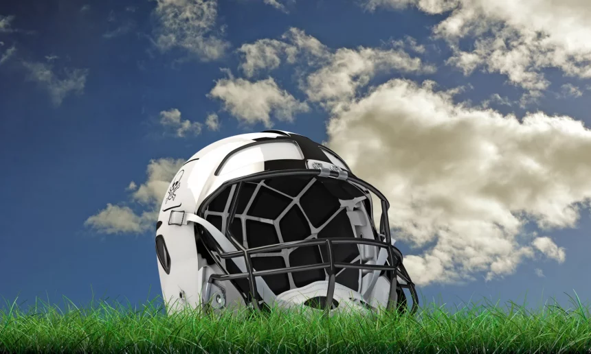 FootballR - NFL BYE Weeks - Bye Week - Woche 7 - Welches Teams hat wann Bye Week? - Ein weißer Footballhelm mit schwarzen Akzenten liegt auf einem grünen Grasfeld unter einem teilweise bewölkten blauen Himmel, als wäre er bereit für die nächste Bye Week. Die Gesichtsmaske des Helms ist schwarz mit einem Gittermuster und das schlanke, moderne Design fällt auf. Kleine Pflanzen rund um das Gras ergänzen die natürliche Kulisse. Diese Beschreibung wurde automatisch generiert.