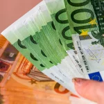 FootballR - NFL - Eine Person hält einen Fächer aus Euro-Scheinen im Wert von 50 bis 200 Euro in den Händen. Die Scheine sind in leuchtenden Farben gehalten, wobei Grün für 100 Euro und Rotbraun für 50 Euro obenauf steht. Vielleicht spart die Person für die Eintrittskarten zum NFL-Spiel in München. Ihre Nägel sind mit Glitzerlack lackiert. Diese Beschreibung wurde automatisch generiert.