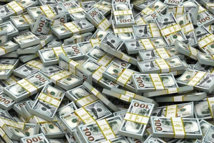 FootballR - NFL - Sunday Ticket - Milliarden Urteil gegen NFL - Ein großer Stapel von 100-Dollar-Scheinen ist gestapelt und mit gelben Bändern zusammengebunden, was einem Betrag von 8 Milliarden Dollar entspricht. Die Stapel sind willkürlich angeordnet, was eine chaotische, aber üppige Darstellung des Geldes ergibt und die hohe Menge und den hohen Wert des Geldes unterstreicht. Diese Beschreibung wurde automatisch generiert.