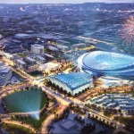 FootballR - NFL - Luftaufnahme eines modernen Stadtgebiets in der Abenddämmerung, darunter das neue NFL-Stadion der Jacksonville Jaguars mit einem durchscheinenden Dach. Die umliegenden Gebäude und Straßen sind gut beleuchtet. Am Himmel über dem Stadion explodieren Feuerwerke. In der Umgebung befinden sich ein Gewässer, Grünflächen und ein Yachthafen mit Booten. Diese Beschreibung wurde automatisch generiert.