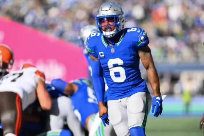 FootballR - NFL - Ein Footballspieler in einem blauen Trikot mit der Nummer 6, Quandre Diggs, und einem silbernen Helm steht während eines Titans-Spiels auf dem Feld. Im Hintergrund sind weitere Spieler zu sehen, darunter einer in einer braun-weißen Uniform. Das Stadion ist voller jubelnder Fans. Diese Beschreibung wurde automatisch generiert.