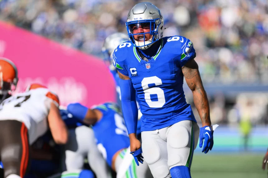 FootballR - NFL - Ein Footballspieler in einem blauen Trikot mit der Nummer 6, Quandre Diggs, und einem silbernen Helm steht während eines Titans-Spiels auf dem Feld. Im Hintergrund sind weitere Spieler zu sehen, darunter einer in einer braun-weißen Uniform. Das Stadion ist voller jubelnder Fans. Diese Beschreibung wurde automatisch generiert.