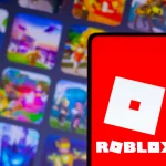 FootballR - NFL - Ein Smartphone mit dem Roblox-Logo, einem weißen, schrägen Quadrat mit einem kleineren, in der Mitte ausgeschnittenen Quadrat auf einem leuchtend roten Hintergrund. Hinter dem Telefon ist der Hintergrund verschwommen, zeigt aber bunte Spielsymbole, darunter NFL Universe Football, die verschiedene Auswahlmöglichkeiten auf der Roblox-Plattform hervorheben. Diese Beschreibung wurde automatisch generiert.