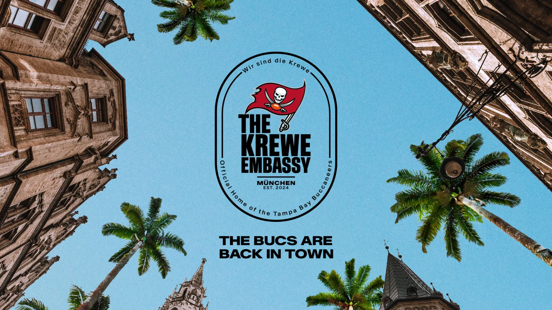 Von unten rahmen Gebäude im europäischen Stil und Palmen einen klaren blauen Himmel ein. In der Mitte befindet sich „The Krewe Embassy“, geschmückt mit einem Piraten-Emblem, das es als offizielles Heimstadion der Tampa Bay Buccaneers in München kennzeichnet. Darunter steht in fettem Text: „Die Bucs sind zurück in der Stadt.“ Diese Beschreibung wurde mit der FootballR KI automatisch generiert.