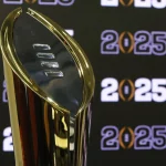 Bowl Tracker - College Football Playoffs - Das Bild zeigt eine goldene Trophäe mit einer glatten, ovalen Spitze und aufwendigen Gravuren, die den Sieg in den College Football Playoffs symbolisiert. Im Hintergrund ist auf einer schwarzen Wand die Zahl „2025“ in mehreren Wiederholungen zu sehen. Die Trophäe ist etwas links vom Rahmen positioniert. Diese Beschreibung wurde automatisch generiert.