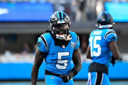 Ein Footballspieler im blau-schwarzen Trikot mit der Nummer 5, Diontae Johnson, brüllt energisch auf dem Feld. Ein weiterer Spieler, Nummer 15, ist im Hintergrund des hell erleuchteten Stadions leicht verschwommen. Diese Beschreibung wurde mit der FootballR KI automatisch generiert.