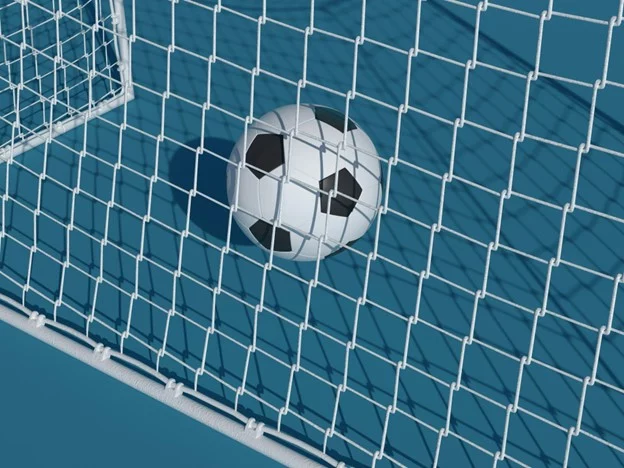 Ein Fußball liegt auf einem blauen Feld am weißen Tornetz. Die schwarz-weißen Felder, die dem klassischen Design eines Fußballs ähneln, bilden einen Kontrast zum Netz und der blauen Oberfläche und deuten auf ein erfolgreiches Tor hin. Sonnenlicht wirft weiche Schatten und betont die Texturen von Netz und Ball. Diese Beschreibung wurde mit der FootballR KI automatisch generiert.