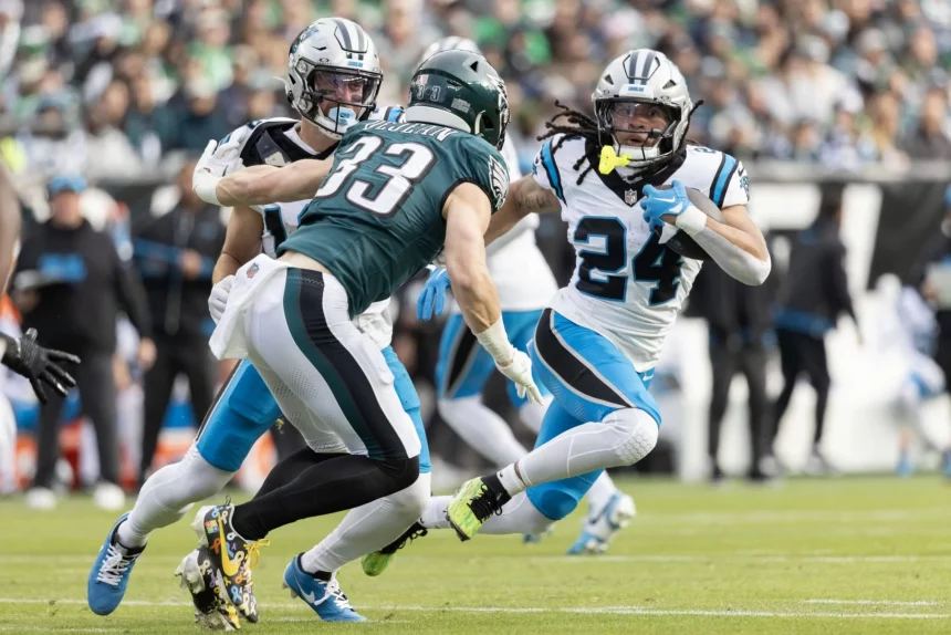 Fußballspieler in Aktion während eines Spiels. Ein Spieler im grünen Trikot, Nummer 33, stürmt mit dem Ball nach vorne, während zwei Spieler in weißen Trikots, Nummer 24 und 7, versuchen, ihn zu tackeln. Das Feld ist grasbewachsen und im unscharfen Hintergrund ist eine große Menschenmenge zu sehen. Diese Beschreibung wurde mit der FootballR KI automatisch generiert.