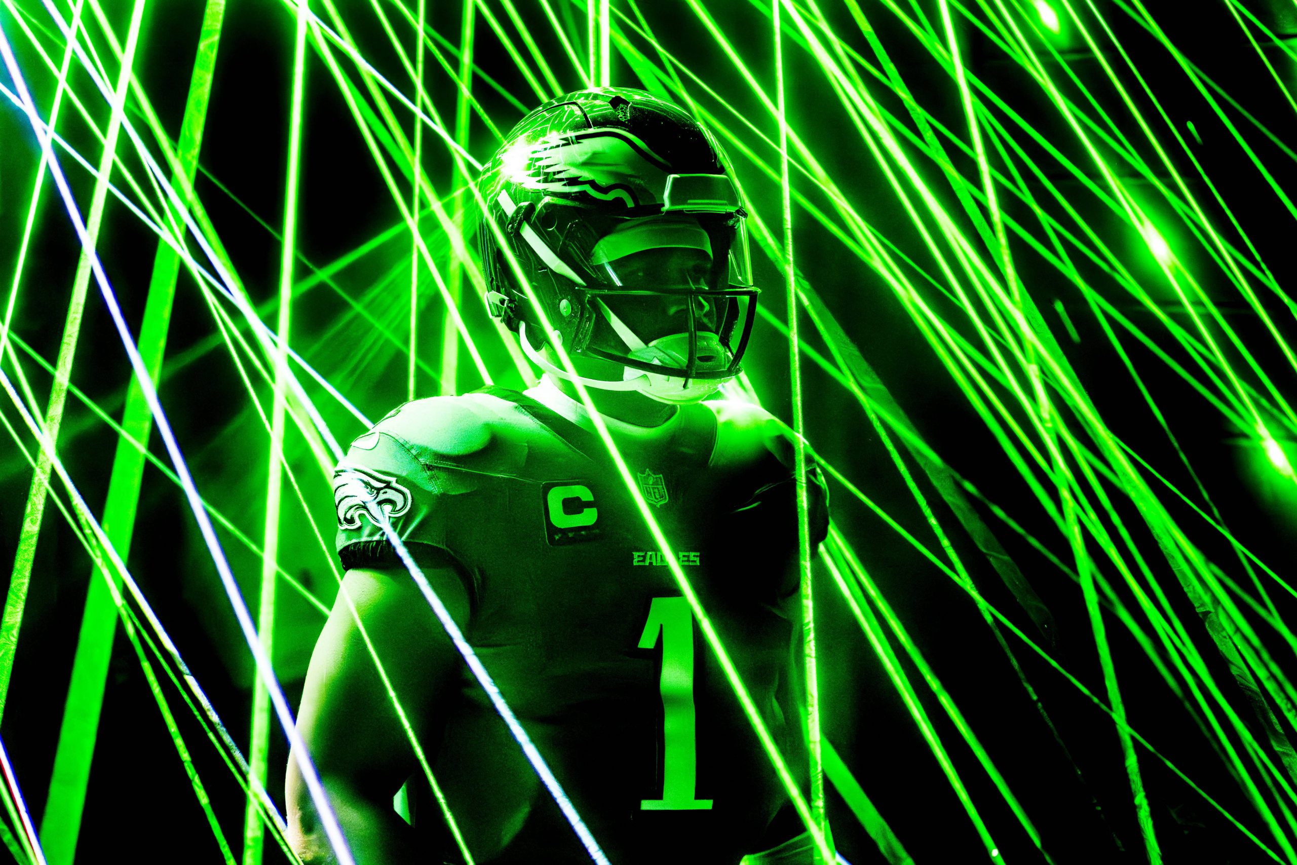 Jalen Hurts mit Helm und Eagles-Trikot mit der Nummer 1 ist von grünen Laserstrahlen umgeben. Die elektrisierende Atmosphäre unterstreicht den konzentrierten Gesichtsausdruck des Spielers, während das Trikot stolz ein Adleremblem auf der Schulter zeigt, das an Jalen Hurts‘ dynamische Energie erinnert. Diese Beschreibung wurde mit der FootballR KI automatisch generiert.