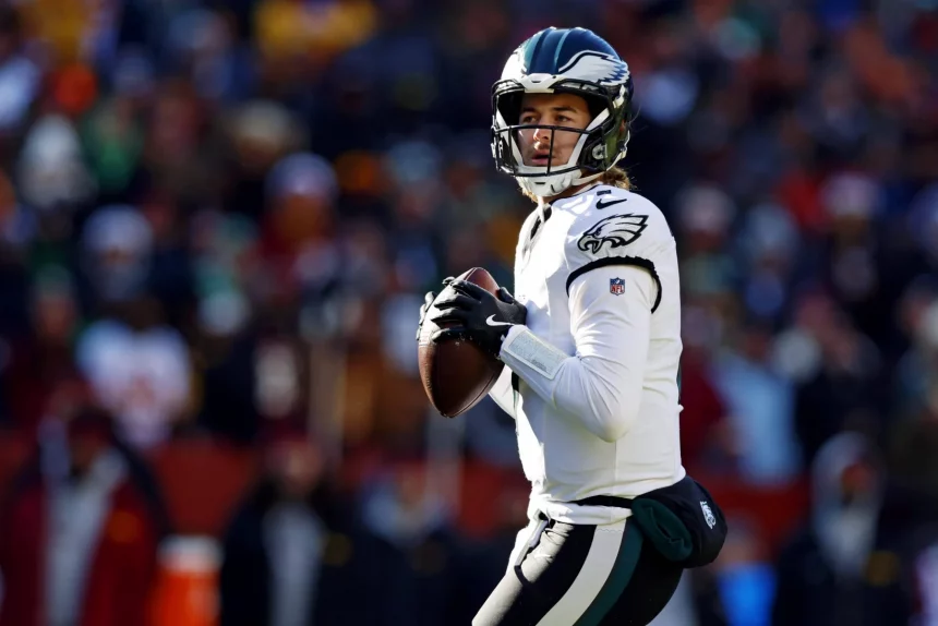 Kenny Pickett in weiß-grüner Uniform hält einen Football und ist bereit, ihn zu werfen. Mit seinem schwarzen Helm mit einem Logo an den Seiten hat er eine verblüffende Ähnlichkeit mit Kenny Pickett. Der unscharfe Hintergrund zeigt eine lebhafte Menge, die die Aufregung des laufenden Spiels einfängt. Diese Beschreibung wurde mit der FootballR KI automatisch generiert.