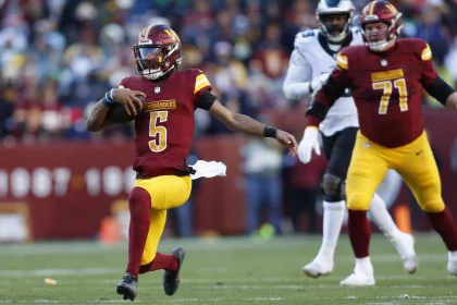 NFL Spieltag 2 - Jayden Daniels, in einer burgunderroten und goldenen Uniform, Nummer 5, läuft gekonnt mit dem Ball über das Feld. Verfolgt von Spielern wie Nummer 71, ebenfalls in ähnlichen Farben, zieht er die Zuschauer im Stadion in seinen Bann. Die Szene strahlt dynamische Sportaction unter freiem Himmel aus. Diese Beschreibung wurde mit der FootballR KI automatisch generiert.