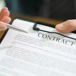 NFL Gehaltsranking 2025 - Eine Person im formellen Anzug hält ein Klemmbrett mit einem NFL Verträge und zeigt mit einem Stift darauf. Der Vertragstext ist teilweise sichtbar, oben ist das Wort „VERTRAG“ fett gedruckt. Der Holztisch im Hintergrund unterstreicht diese professionelle Umgebung. Diese Beschreibung wurde mit der FootballR KI automatisch generiert.