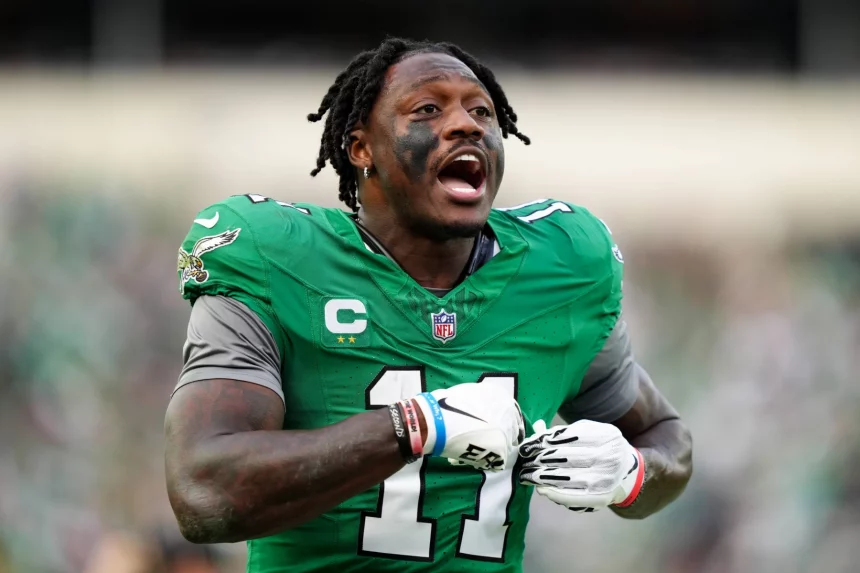 A.J. Brown in einem grünen Trikot mit der Nummer 11 und schwarzen Streifen unter den Augen gestikuliert energisch auf dem Feld. Er verkörpert die Intensität von A.J. Brown während dieses Playoff-Spiels. Mit grauen Handschuhen und einem Helm mit Logoaufklebern strahlt er vor dem verschwommenen Hintergrund eines spannenden Spiels. Diese Beschreibung wurde mit der FootballR KI automatisch generiert.