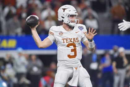 Quinn Ewers in einer weißen Uniform der Texas Longhorns mit der Nummer 3, wahrscheinlich Quinn Ewers, ist bereit, einen Football zu werfen. Er trägt einen weißen Helm mit dem ikonischen Logo der Longhorns und steht in der Mitte des Feldes, umgeben von verschwommenen Zuschauern im Hintergrund. Diese Beschreibung wurde mit der FootballR KI automatisch generiert.