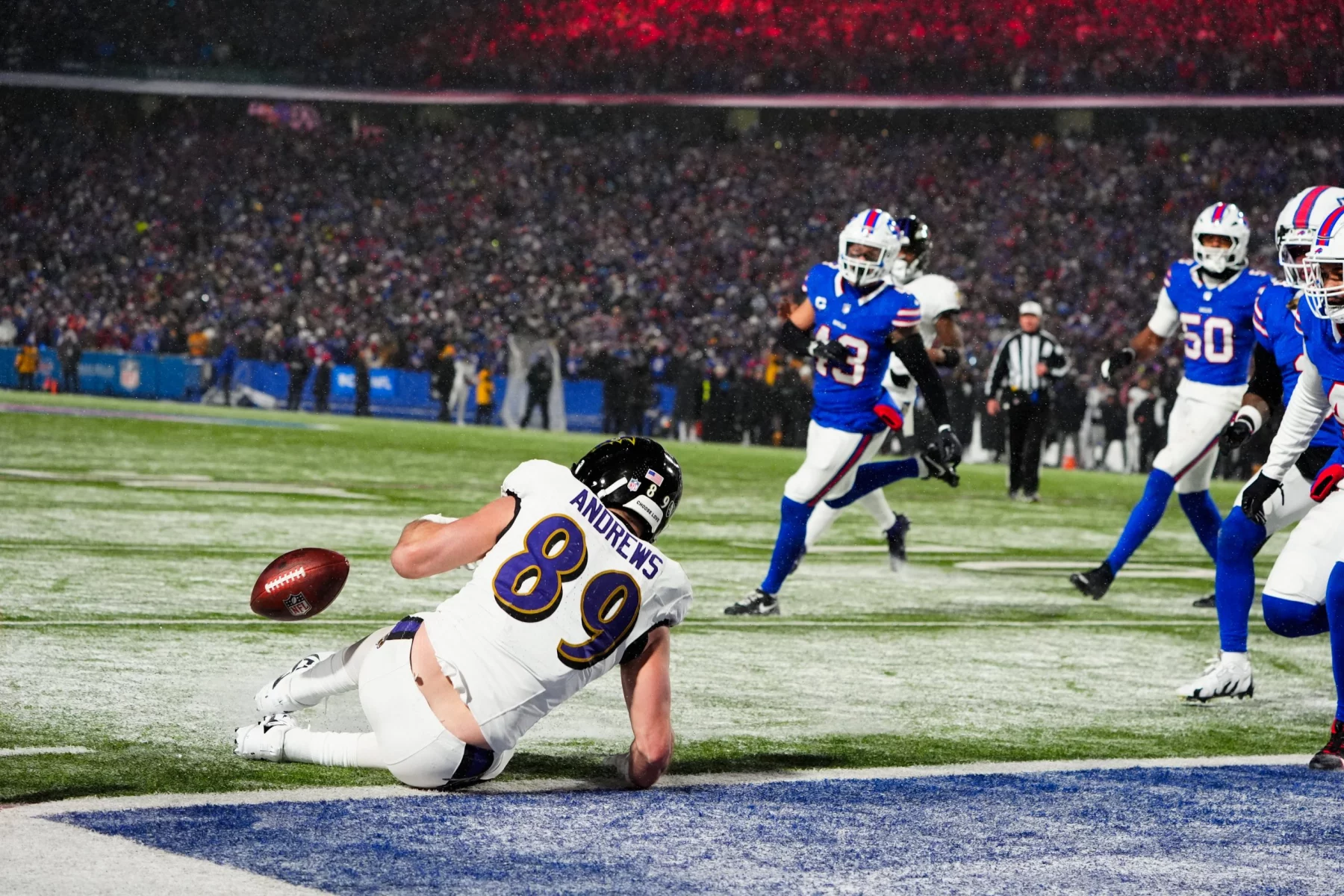 NFL Playoffs Divisional Round - Ein Footballspieler mit der Nummer 89 und der Aufschrift „ANDREWS“ hechtet in einem spannenden NFL-Playoff-Divisional-Round-Spiel in Richtung Endzone und streckt sich nach dem Ball, der gerade außer Reichweite ist. Spieler in blauen Trikots und ein Schiedsrichter sind im Hintergrund zu sehen, während die Zuschauer die Tribünen unter Stadionbeleuchtung füllen. Diese Beschreibung wurde mit der FootballR KI automatisch generiert.