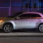 Nach dem Championship Game: Ein silberner SUV steht nachts auf einer schwach beleuchteten Straße, die an ein spannendes Meisterschaftsspiel erinnert. Polizeiabsperrungen spannen sich über die gesamte Länge und kennzeichnen den Tatort. Im Hintergrund spiegeln sich bunte Lichter eines nahe gelegenen Gebäudes in der Oberfläche des Autos und werfen einen unheimlichen Schein durch den Maschendrahtzaun. Diese Beschreibung wurde mit der FootballR KI automatisch generiert.