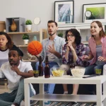 Gruppe von Freunden vor dem Fernseher im Wohnzimmer.
