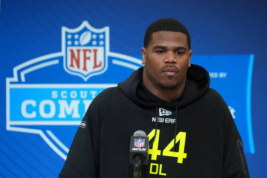 Abdul Carter in einem schwarzen Kapuzenpullover mit der Aufschrift „44“ steht ernst vor einem Mikrofon mit dem NFL-Logo. Der blaue Hintergrund mit dem Scouting Combine-Branding deutet auf seine Entschlossenheit hin. Abdul Carters intensive Konzentration lässt darauf schließen, dass er für den nächsten großen Schritt in seiner Karriere bereit ist. Diese Beschreibung wurde mit der FootballR KI automatisch generiert.