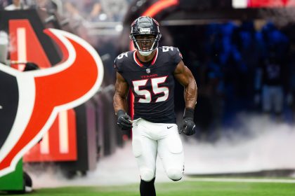Danielle Hunter, in einem schwarzen Trikot mit der Nummer 55, stürmt aus einem Tunnel auf das Footballfeld. Hinter ihm quillt Rauch auf, während er Helm und weiße Hose anzieht. Ein großes Stierkopf-Logo kennzeichnet den Tunneleingang, im Hintergrund jubeln die Fans lautstark. Diese Beschreibung wurde mit der FootballR KI automatisch generiert.