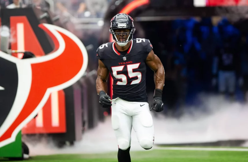 Danielle Hunter, in einem schwarzen Trikot mit der Nummer 55, stürmt aus einem Tunnel auf das Footballfeld. Hinter ihm quillt Rauch auf, während er Helm und weiße Hose anzieht. Ein großes Stierkopf-Logo kennzeichnet den Tunneleingang, im Hintergrund jubeln die Fans lautstark. Diese Beschreibung wurde mit der FootballR KI automatisch generiert.