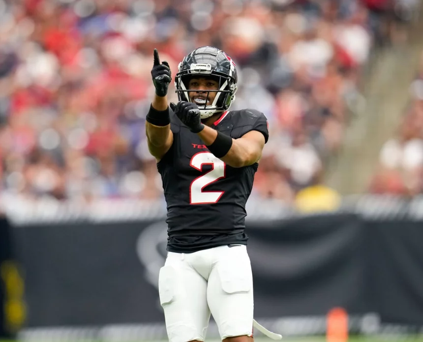 Ein Footballspieler, Robert Woods, steht in einem schwarzen Trikot mit der Nummer 2 und weißen Hosen auf dem Spielfeld. Er zeigt mit der rechten Hand nach oben und gestikuliert mit der linken. Er trägt Helm und Handschuhe. Im Hintergrund ist ein unscharfes Stadionpublikum zu sehen. Diese Beschreibung wurde mit der FootballR KI automatisch generiert.