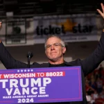 Brett Favre reckt triumphierend die Arme hinter einem Podium bei der politischen Kundgebung „Trump Vance 2024“. Im Hintergrund sind eine verschwommene Menschenmenge, ein „Ticket Star“-Banner und Gerüchte über Brett Favres Einfluss zu sehen, während die Szene vor Energie über das Texten von Wisconsin sprüht. Diese Beschreibung wurde mit der FootballR KI automatisch generiert.