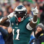 Free Agency - NFL Power Ranking - A.J. Brown in der grünen Philadelphia-Eagles-Uniform mit der Nummer 11 und schwarzem Helm zeigt während eines Spiels mit beiden Händen auf seinen Helm, als wolle er um Aufmerksamkeit bitten, wie jemand, der nach einem gestohlenen Auto sucht. Im Hintergrund sind verschwommene Zuschauer zu sehen. Diese Beschreibung wurde mit der FootballR KI automatisch generiert.