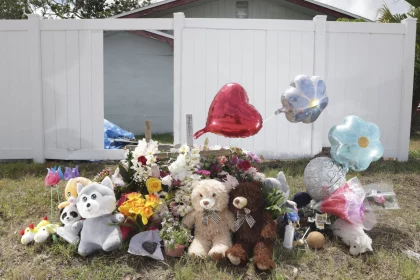 Miami Hurricanes Spieler in Unfall verwickelt: Ein Denkmal mit Teddybären, Stofftieren, Blumen und herz- und blumenförmigen Luftballons steht auf dem Rasen vor einem weißen Zaun und einem Haus – einige Gegenstände ehren die Verstorbenen mit herzlichen Botschaften der Erinnerung und des Beileids. Diese Beschreibung wurde mit der FootballR KI automatisch generiert.