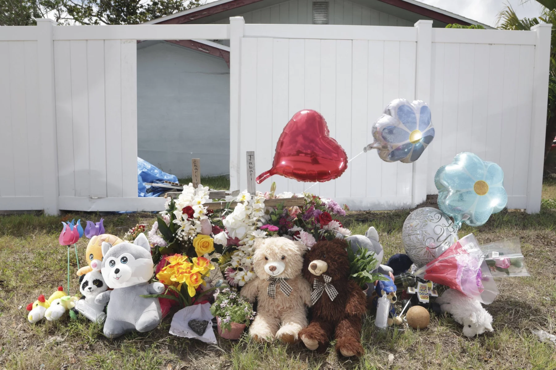 Miami Hurricanes Spieler in Unfall verwickelt: Ein Denkmal mit Teddybären, Stofftieren, Blumen und herz- und blumenförmigen Luftballons steht auf dem Rasen vor einem weißen Zaun und einem Haus – einige Gegenstände ehren die Verstorbenen mit herzlichen Botschaften der Erinnerung und des Beileids. Diese Beschreibung wurde mit der FootballR KI automatisch generiert.