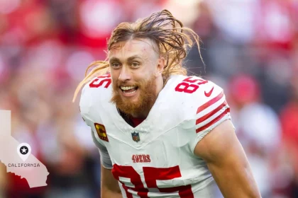 Ein Footballspieler, George Kittle, mit langen blonden Haaren und Bart, der ein weißes Trikot mit roten Streifen und der Nummer 85 trägt, schreit aufgeregt auf dem Feld – vielleicht feiert er Tight-End-Gehälter. In der Ecke ist der Umriss von Kalifornien mit einem Stern zu sehen. Diese Beschreibung wurde mit der FootballR KI automatisch generiert.
