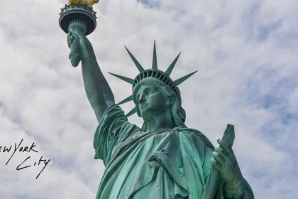 Football x Football - Eine Nahaufnahme der Freiheitsstatue vor einem bewölkten Himmel. Ihre erhobene Fackel und Krone sind sichtbar. Der handgeschriebene Text „New York City x Football“ erscheint in Schwarz auf der linken Seite des Bildes. Diese Beschreibung wurde mit der FootballR KI automatisch generiert.