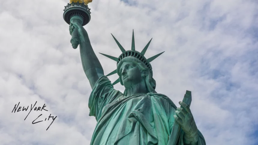 Football x Football - Eine Nahaufnahme der Freiheitsstatue vor einem bewölkten Himmel. Ihre erhobene Fackel und Krone sind sichtbar. Der handgeschriebene Text „New York City x Football“ erscheint in Schwarz auf der linken Seite des Bildes. Diese Beschreibung wurde mit der FootballR KI automatisch generiert.