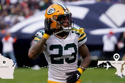 Ein Footballspieler der Green Bay Packers, Jaire Alexander, im Trikot mit der Nummer 23, hält sich auf dem Spielfeld das Ohr zu. Darunter verbindet eine gestrichelte Linie ein Symbol von Wisconsin mit einem Symbol von Maryland, was auf eine Reise zwischen den beiden Staaten hinweist. Diese Beschreibung wurde mit der FootballR KI automatisch generiert.