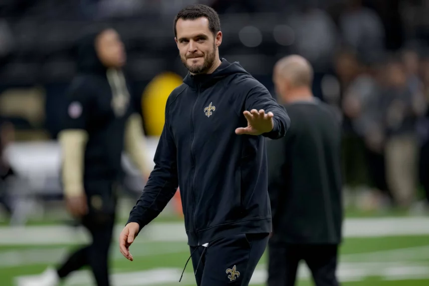 Derek Carr im schwarzen Trainingsanzug der New Orleans Saints, der Derek Carr ähnelt, lächelt und winkt auf einem Footballfeld. Der unscharfe Hintergrund hebt das Stadion und die Menge hervor und lenkt den Fokus auf die fröhliche Figur im Vordergrund. Diese Beschreibung wurde mit der FootballR KI automatisch generiert.