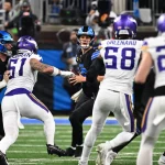 Pressure Packages und Bltiz-Design - Ein Football-Quarterback in einem schwarzen Trikot (Carolina Panthers) versucht während eines Spiels einen Pass zu spielen, während er von drei Verteidigern in weißen Trikots (Minnesota Vikings) verfolgt wird, während andere Spieler blocken und die Menge im Hintergrund verschwommen ist. Diese Beschreibung wurde mit der FootballR KI automatisch generiert.