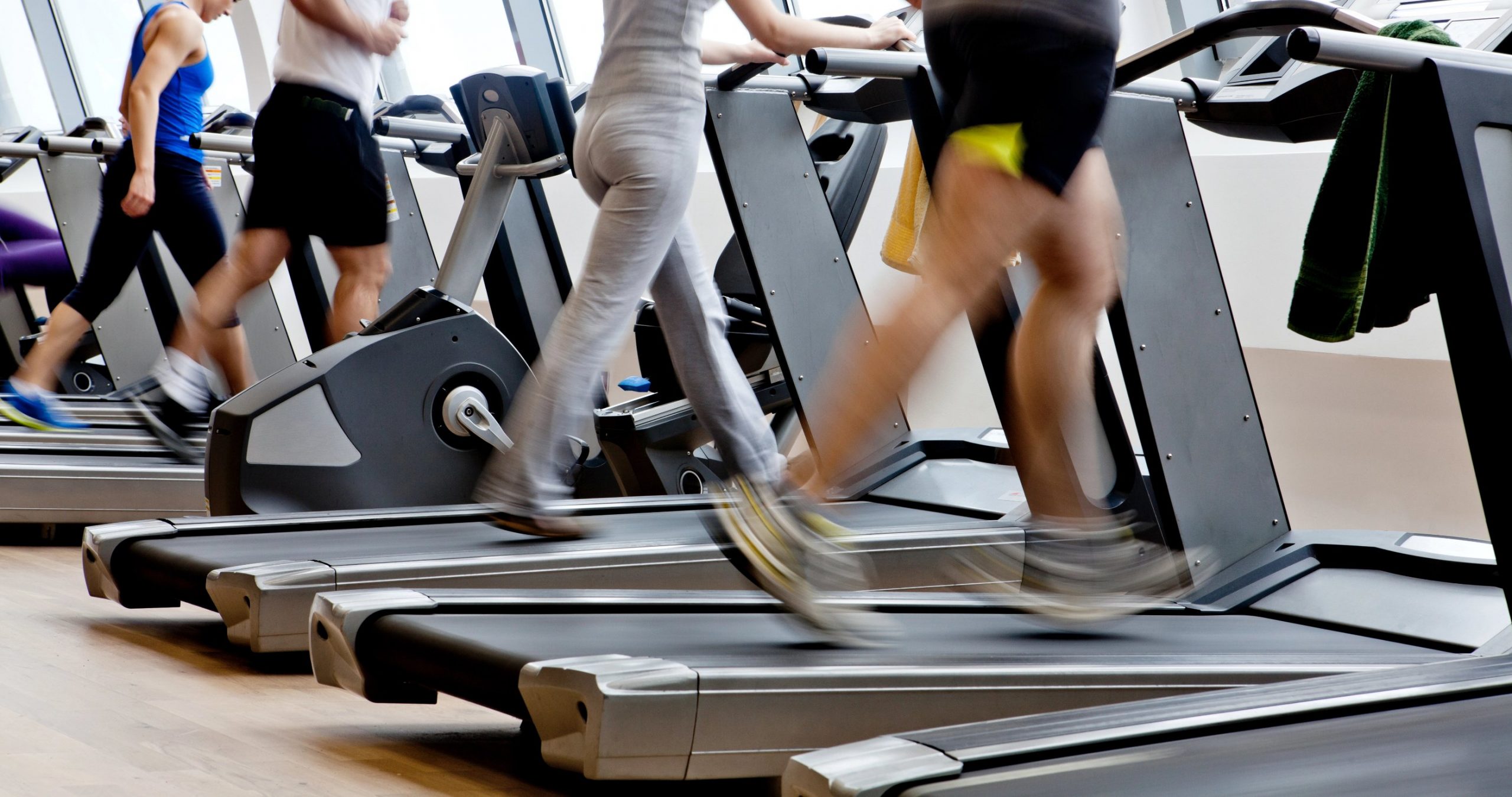 Eine Reihe von Menschen trainiert auf Laufbändern in einem modernen Fitnessstudio. Nur ihre Unterkörper sind zu sehen. Der Holzboden und das helle Licht der großen Fenster schaffen eine offene Atmosphäre - perfekt für Fitnessfreaks, die von Amazon Prime Day Angeboten inspiriert sind. Diese Beschreibung wurde mit der FootballR KI automatisch generiert.