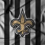 Paris - New Orleans Saints - Ein zerknitterter Stoff mit abwechselnd schwarzen und grauen vertikalen Streifen. In der Mitte befindet sich eine große goldene Fleur-de-Lis, das ikonische Logo der New Orleans Saints. Die Falten des Stoffes erzeugen Schatten und Textur, die das Design der neuen Farbe noch besser zur Geltung bringen. Diese Beschreibung wurde mit der FootballR KI automatisch generiert.