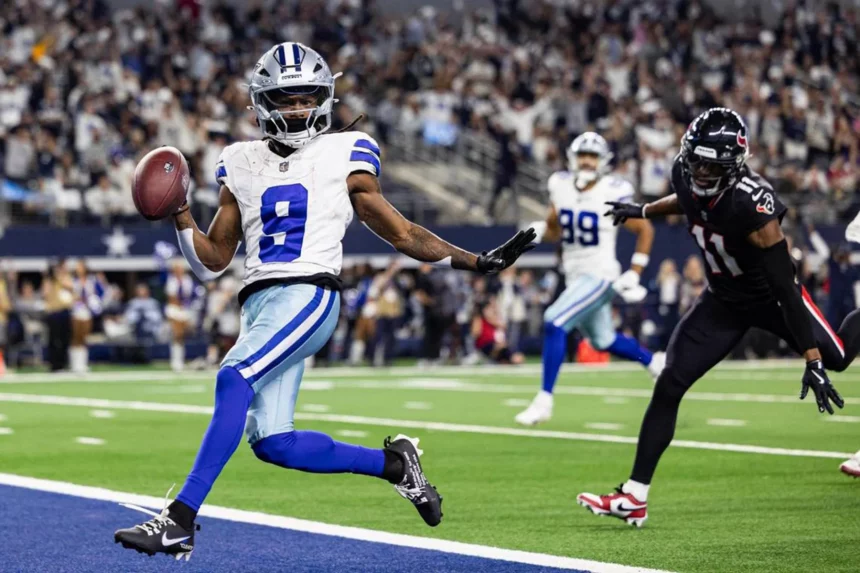 Der Spieler der Dallas Cowboys, KaVontae Turpin mit der Nummer 9, hält einen Football in der Hand und jubelt, als er in die Endzone läuft. Ein Falcons-Verteidiger in Schwarz und Rot versucht, ihn zu verfolgen, während im Hintergrund jubelnde Fans das Stadion füllen. Diese Beschreibung wurde mit der FootballR KI automatisch generiert.