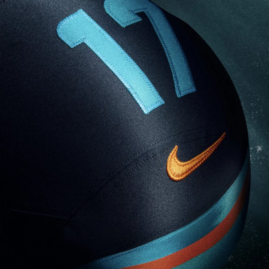 Nahaufnahme eines NFL Rivalries-Trikots mit der Nummer 17 in leuchtendem Blau, einem orangefarbenen Nike-Swoosh-Logo und einem blauen Streifen mit orangefarbenem Akzent. Die Textur des Stoffes und die Nähte sind deutlich sichtbar. Diese Beschreibung wurde mit der FootballR KI automatisch generiert.