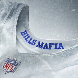Nahaufnahme eines weißen NFL-Football-Trikots, Teil der NFL Rivalries-Trikots-Kollektion, mit "BILLS MAFIA"-Stickerei in Blau im Kragen. Das NFL-Schild-Logo ist in der Nähe des Halsausschnitts vor einem strukturierten Hintergrund mit weißem und grauem Farbverlauf zu sehen. Diese Beschreibung wurde mit der FootballR KI automatisch generiert.
